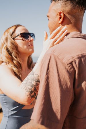An intimate moment captured between a couple on a sunny coastal cliff.