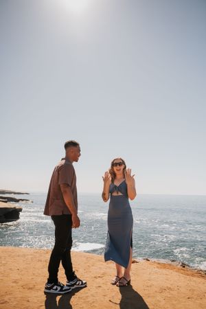 Two people react with joy during a special moment at an oceanside cliff.