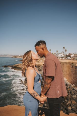 Couple sharing a romantic moment on coastal cliffs overlooking the ocean.