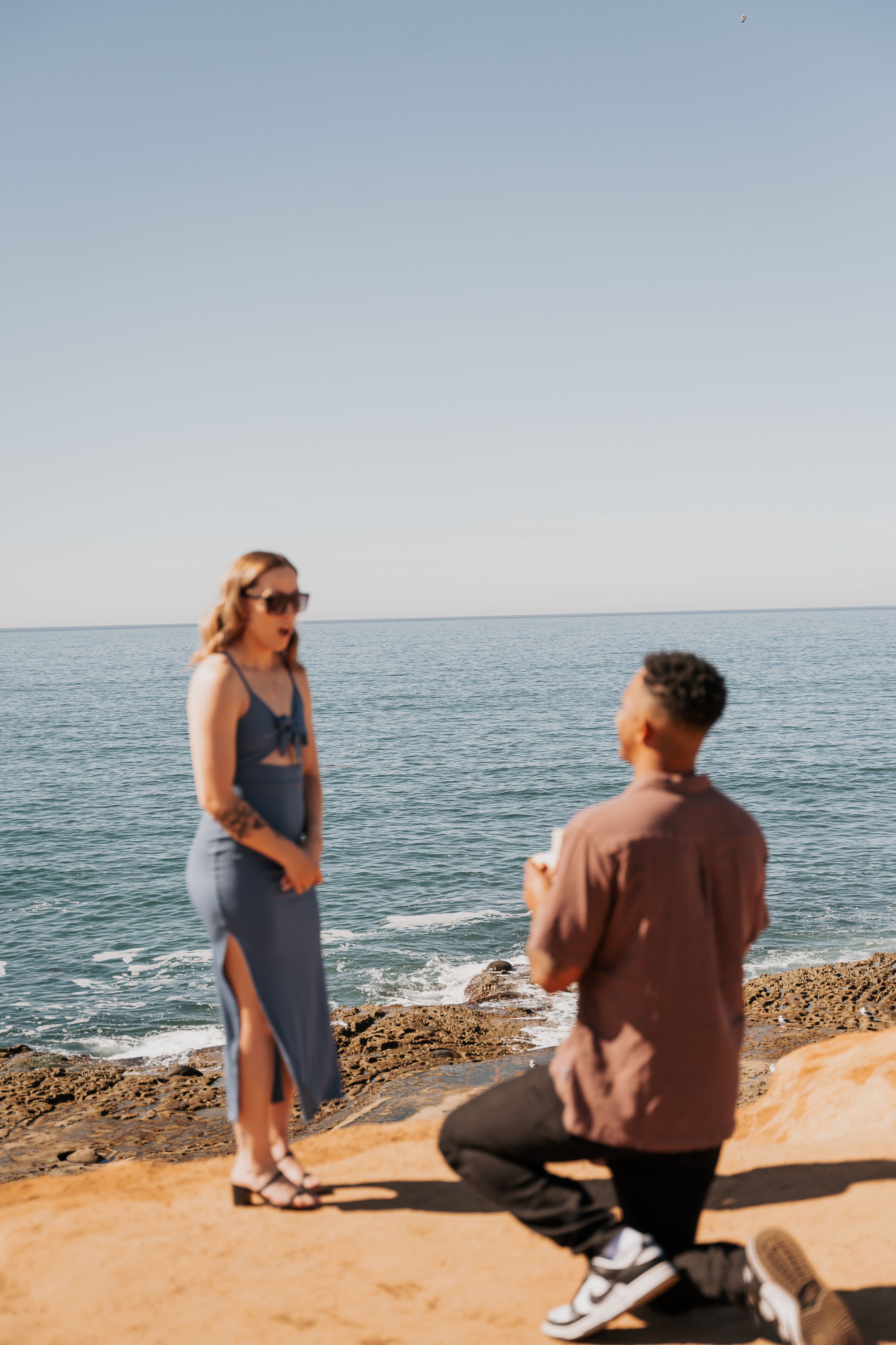 A special moment unfolds at a coastal cliff as a couple shares a memorable occasion.