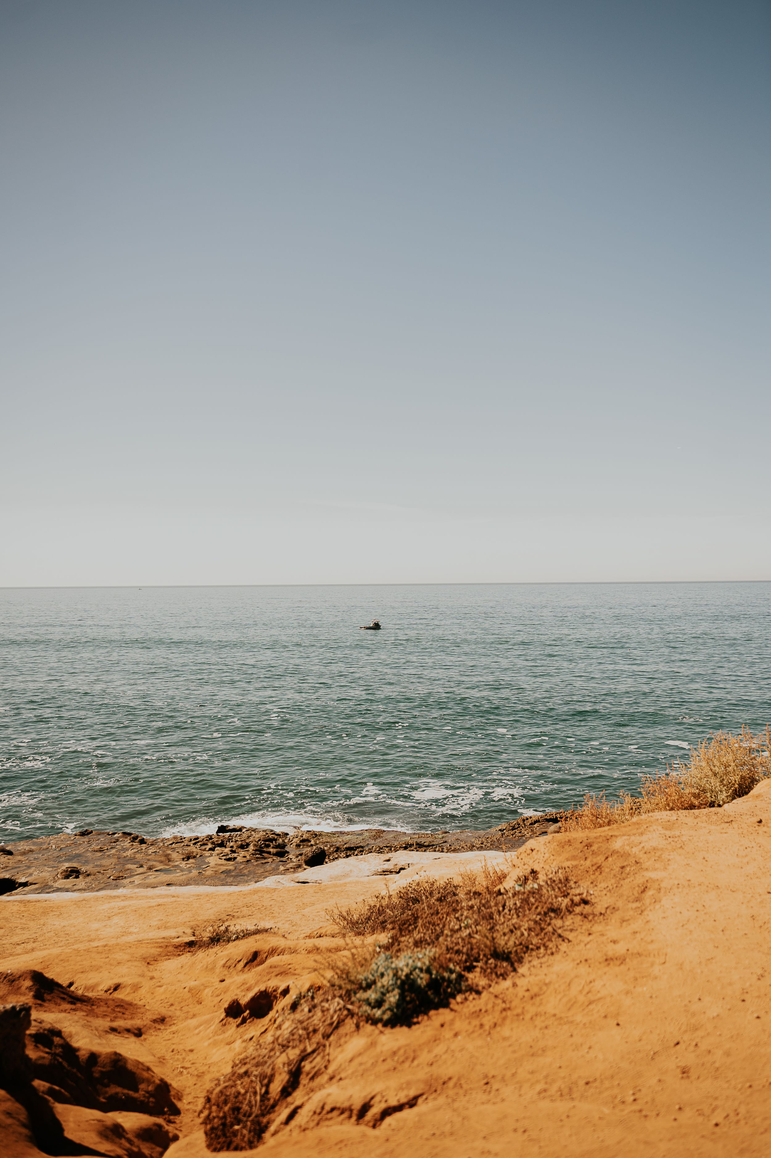 Scenic coastal landscape with orange cliffs overlooking the blue ocean horizon.