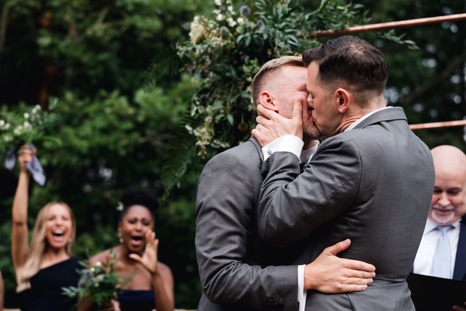 Joyful wedding ceremony moment with guests celebrating in the background.