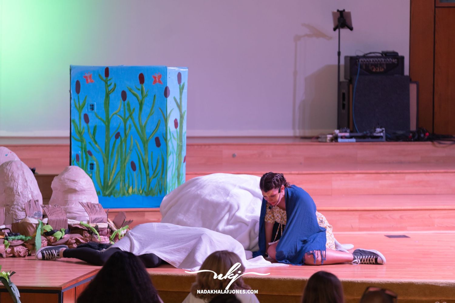 Stage scene with green lighting effects and theatrical set pieces visible in background.