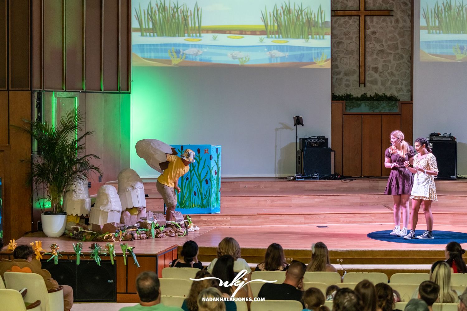 Stage performance with decorative props and scenery depicting a waterside setting.