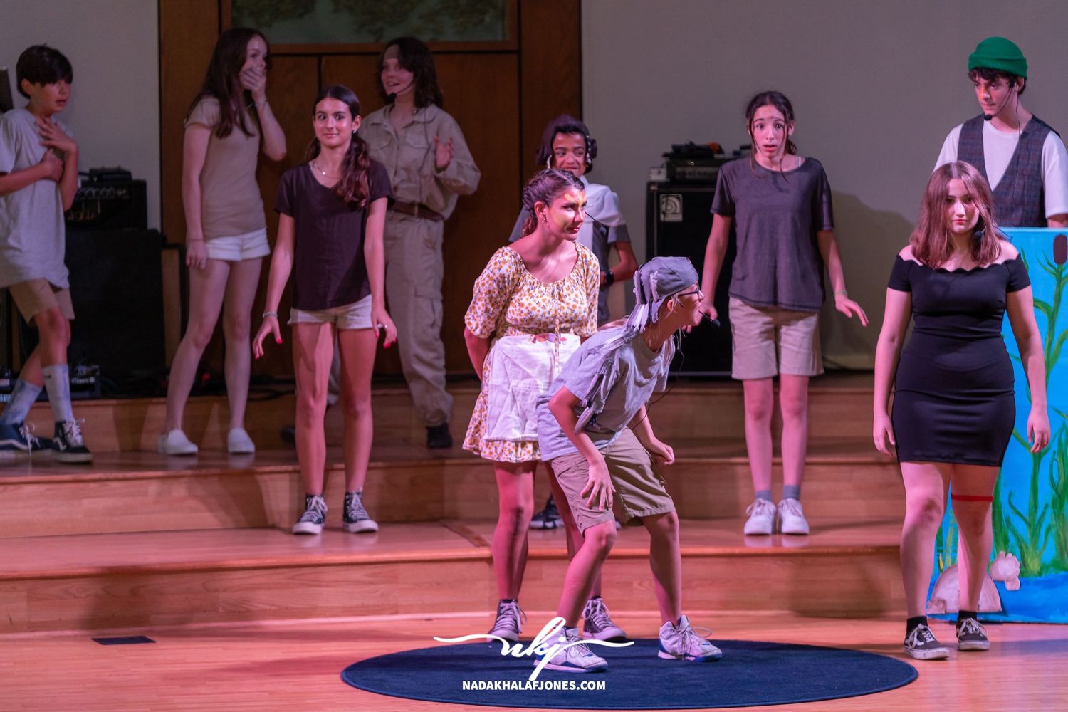 Performers interact on stage during a theatrical production with colorful set pieces.