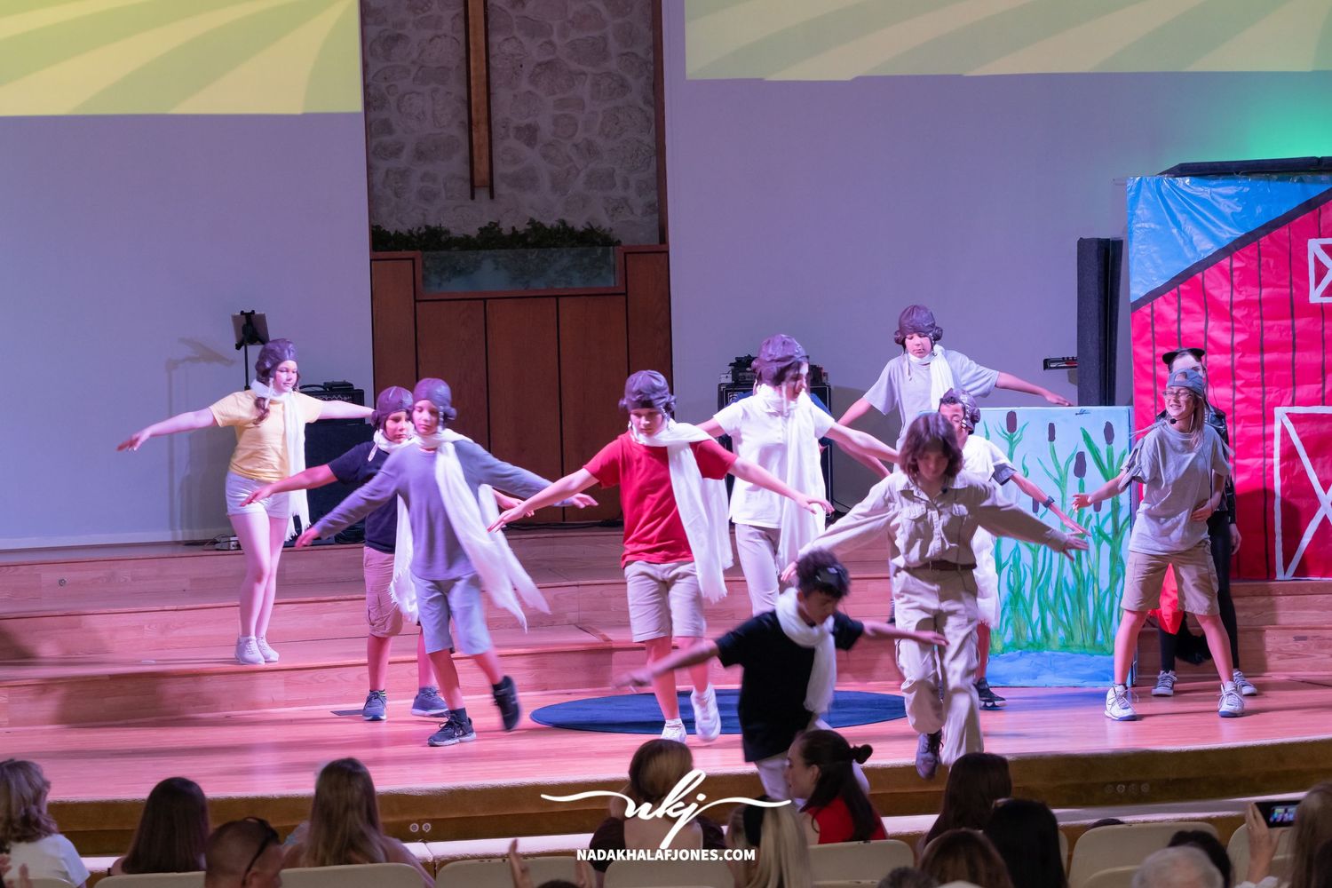 Dance sequence on stage with performers in dramatic poses against painted scenery backdrop.