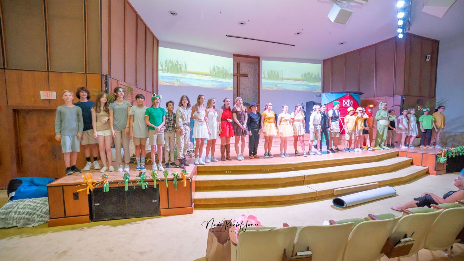 Wide view of theater stage showing full cast performance and auditorium seating.