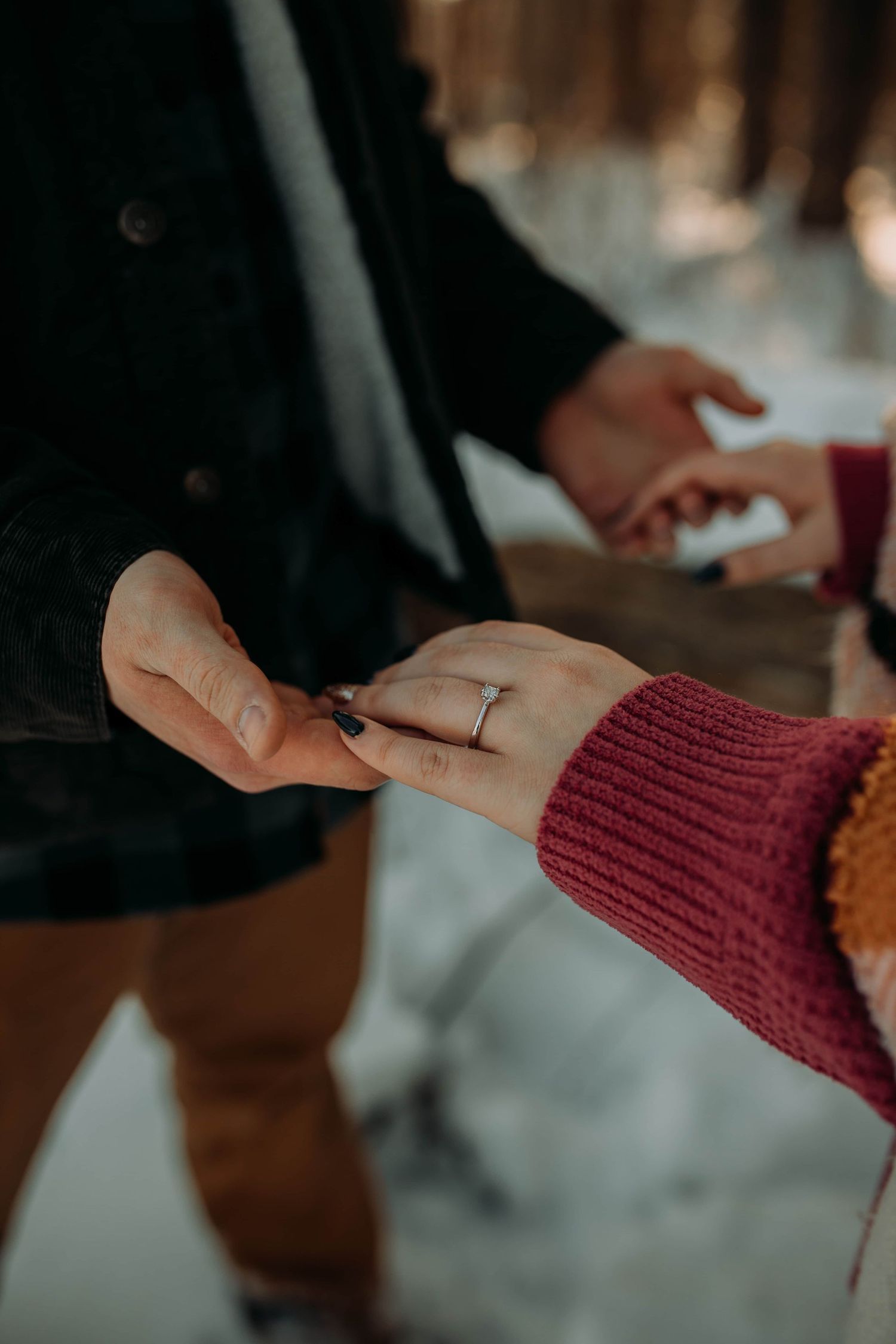 Couple-holding-hands-engagement-ring-snow