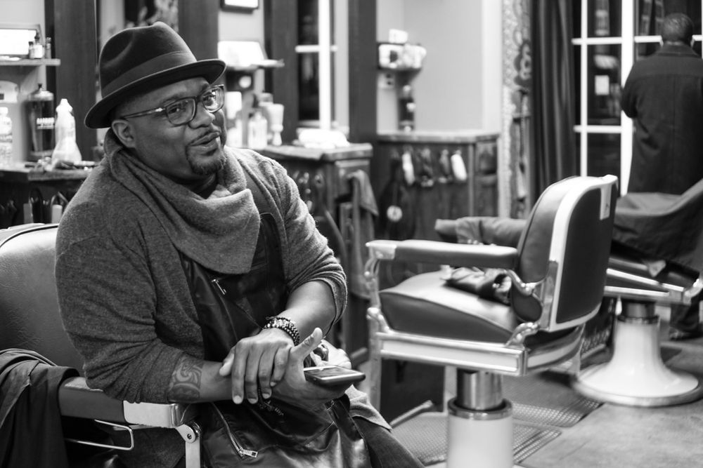 Charles Blade, barber and business owner, sits in a chair at his Oakland shop