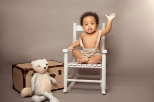Milestone photoshoot featuring a child taking their first steps captured in a bright, cheerful studio.