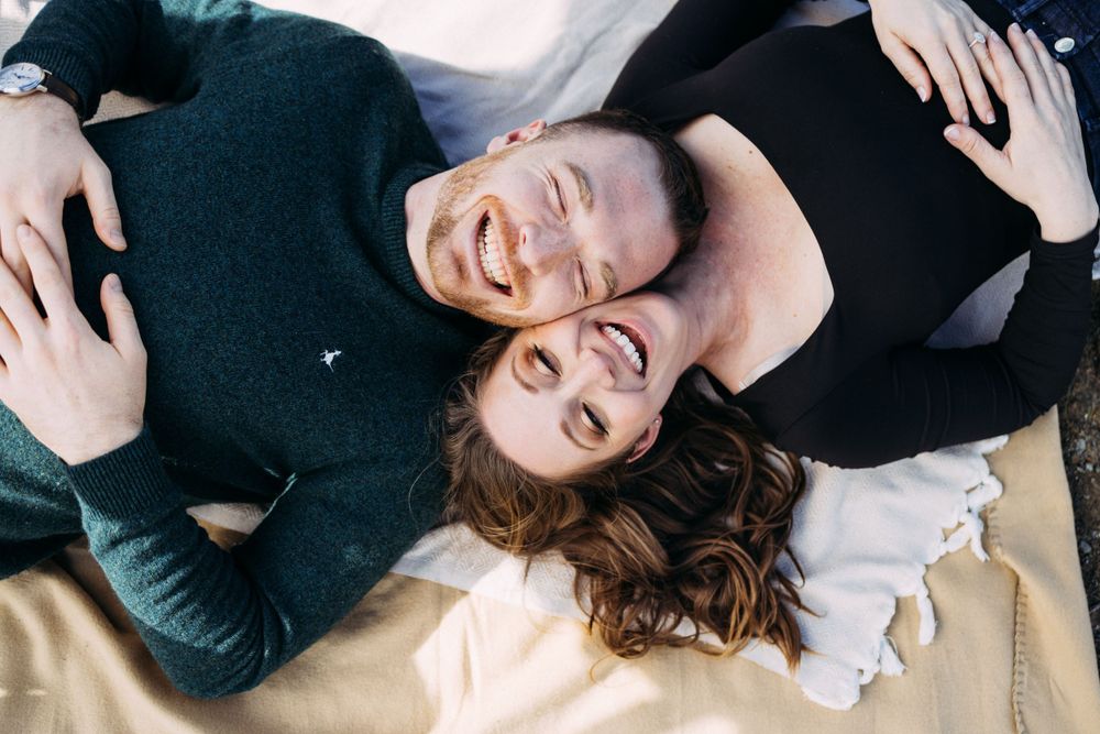 Engagement photo laying down on blanket and laughing