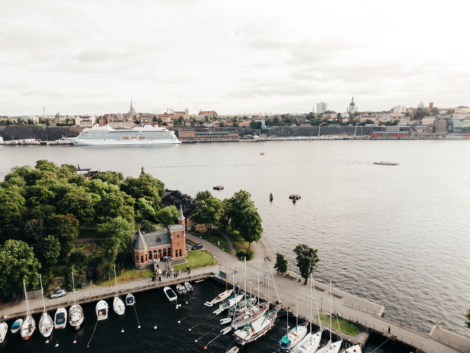 Harbor view with boats docked along waterfront and city skyline in background during daytime.