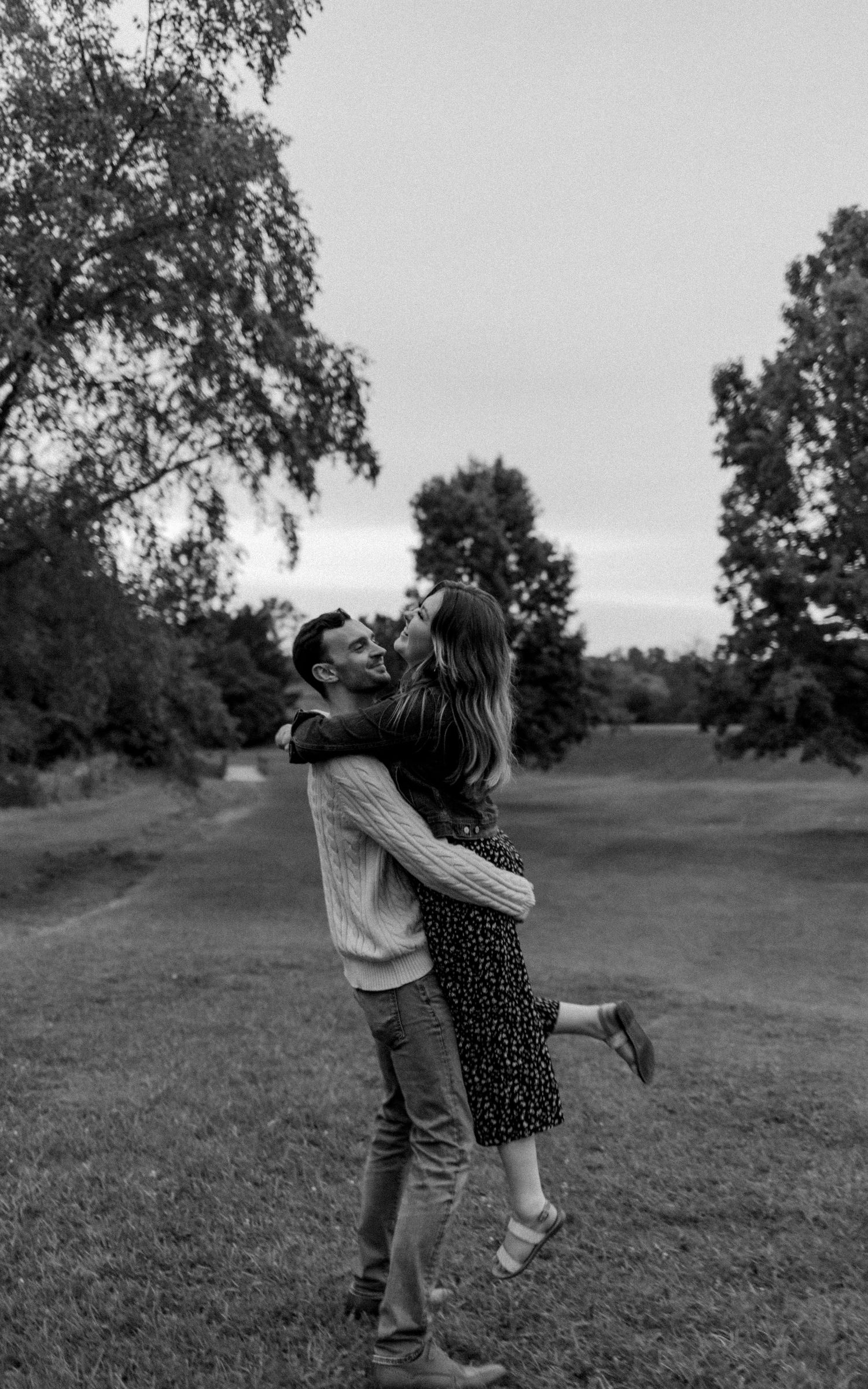 A joyful black and white photo of a couple embracing in a park.