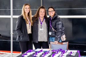Event display table with purple branded materials and promotional items against dark background.
