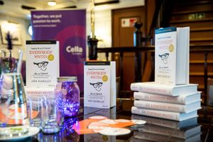 Display of business books and marketing materials with purple lighting effects on dark table.
