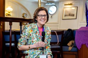 Professional wearing colorful floral blazer speaks at business event in elegant venue.