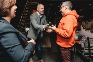 People in business attire having conversation at indoor networking event.