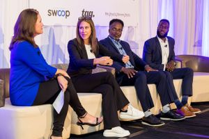 Panel discussion featuring four speakers seated on white chairs against branded backdrop.