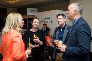 Professional networking event with attendees enjoying beverages and conversation.