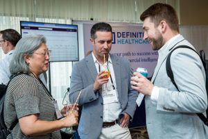 Conference attendees discussing near a healthcare company exhibition booth display.