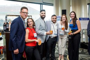 Group of business professionals networking at a corporate event with drinks.