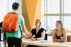 Registration or check-in desk with staff greeting attendee at conference.