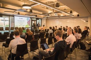 Business conference audience seated in rows listening to presentation in modern office space.