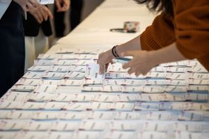 Close-up of hands arranging paper pieces on a collaborative display board.