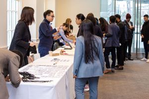 Students gather around registration tables at a business school event.