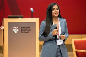 Business presenter speaks at Harvard Business School podium during conference event.
