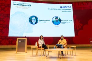 Conference stage with two speakers and presentation screen showing HubSpot branding.
