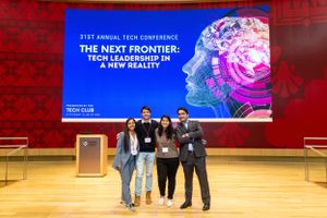 Group photo in front of tech conference banner showing Next Frontier theme.