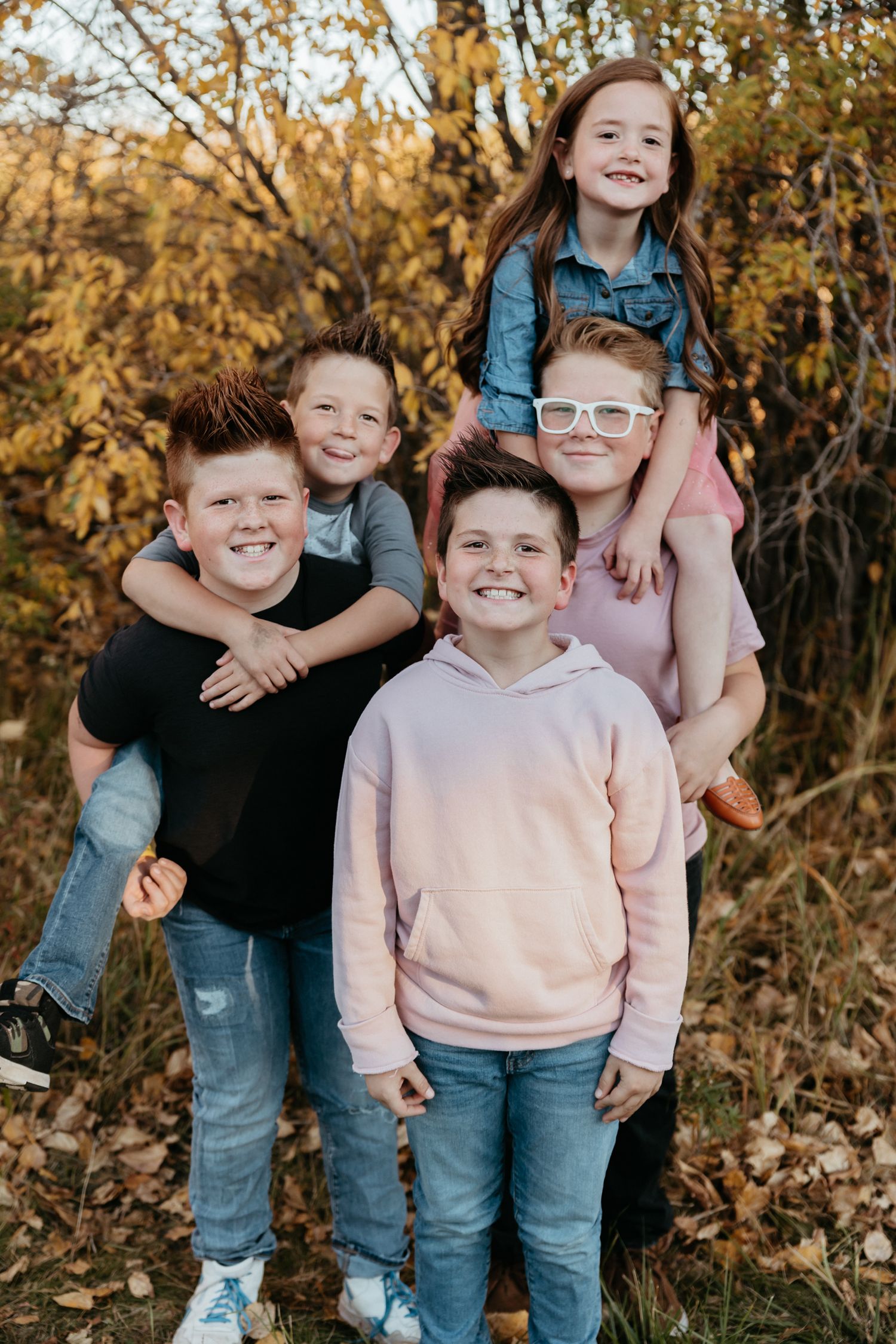 Group of children in casual clothing posing together outdoors during autumn.