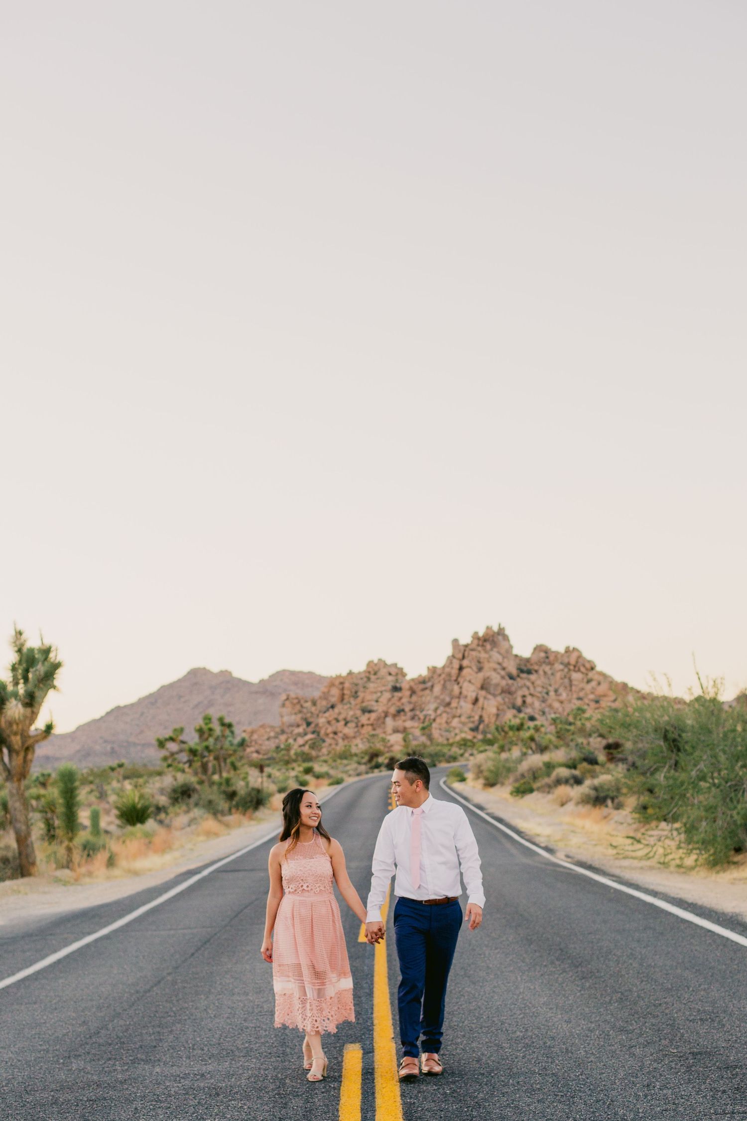 Romantic desert engagement session on an empty road with mountains in the background.
