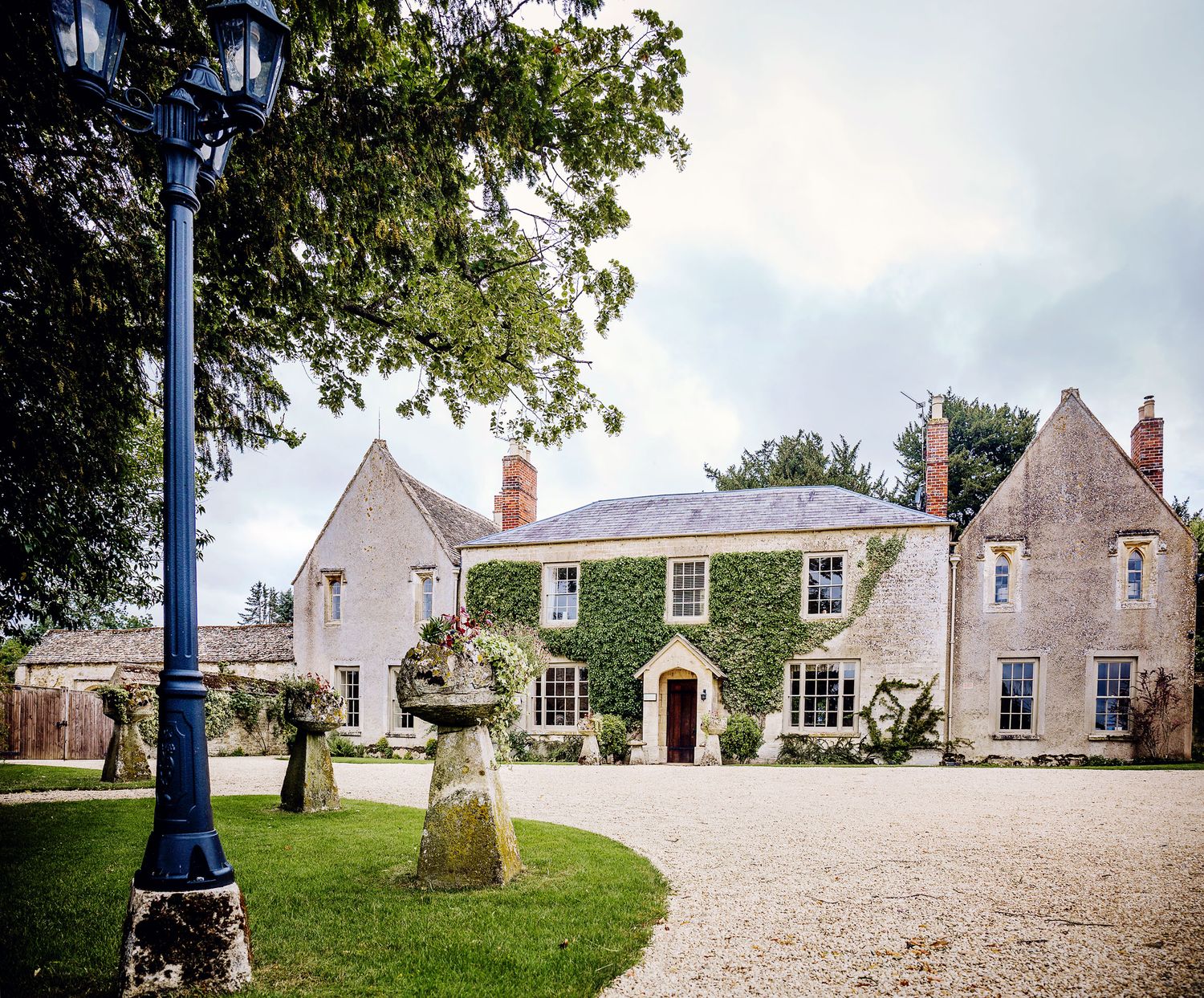 Elegant Georgian manor house with manicured grounds and decorative stone fountain in foreground.