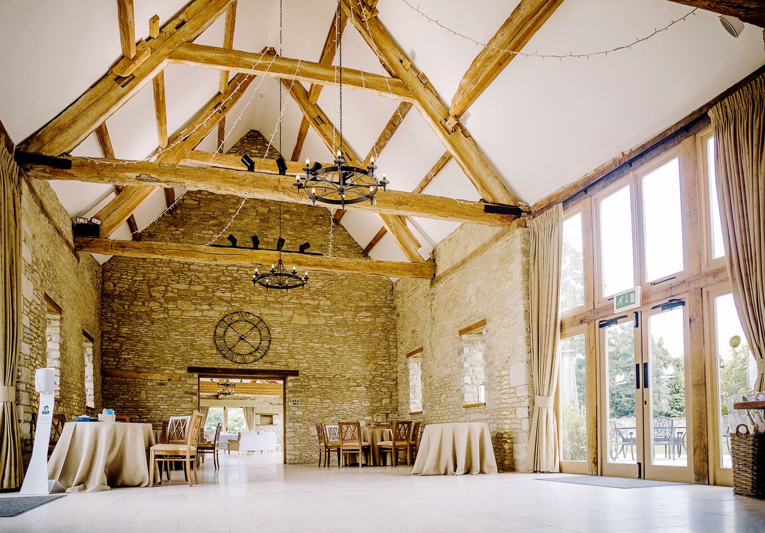 Rustic barn reception hall with exposed wooden beams and stone walls ready for an elegant event.