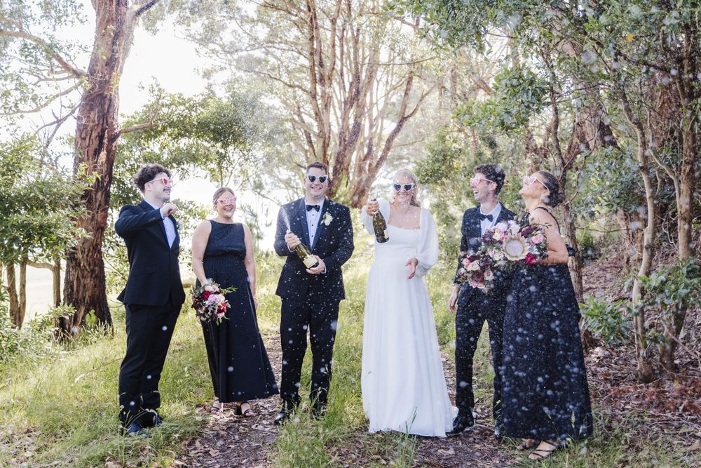 Bridal party gathers in a wooded area for casual wedding photos.
