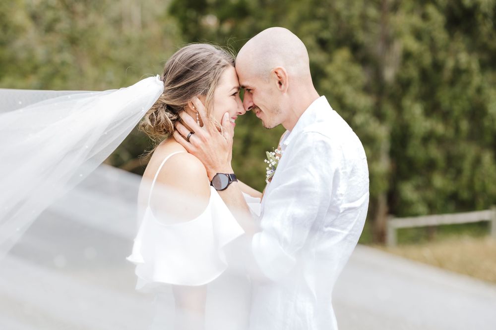 A romantic wedding moment captured with flowing veil in natural outdoor setting.
