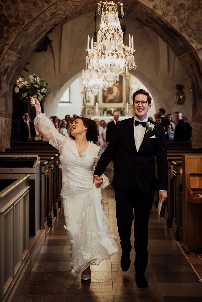 Bruden får feeling och sjunger på vägen ut ur kyrkan. Bröllopsfotografering i Bromma kyrka utanför Stockholm.