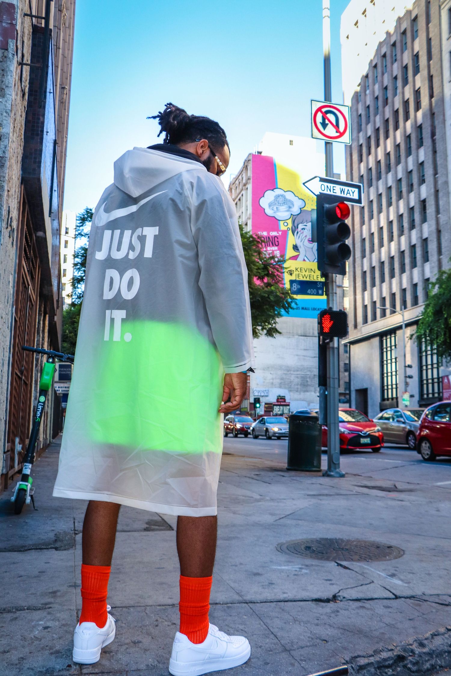 Urban fashion photography featuring transparent Nike jacket and red socks on city street.
