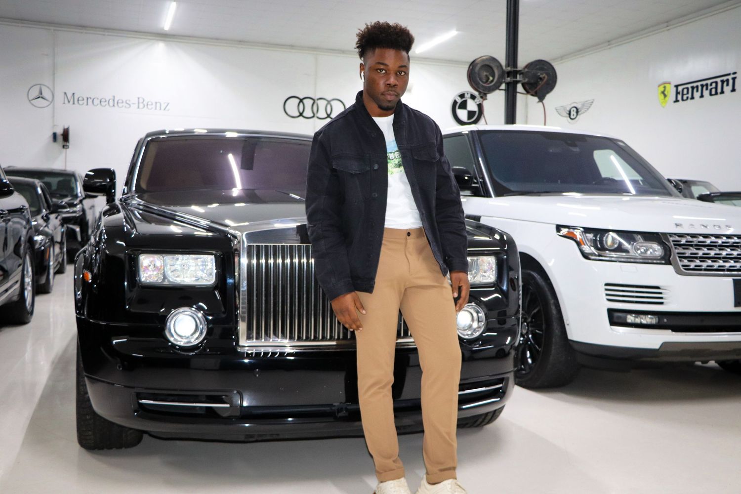 Casual fashion shoot in luxury car showroom featuring Rolls Royce and Range Rover vehicles.