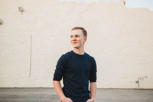 A casual portrait against a plain white wall in natural lighting.