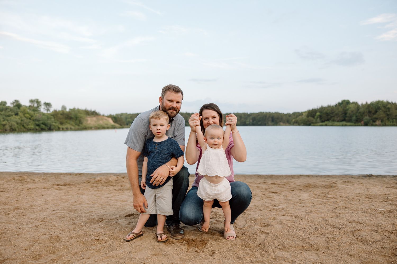 Family enjoying beach day together at lakeside on sandy shore.