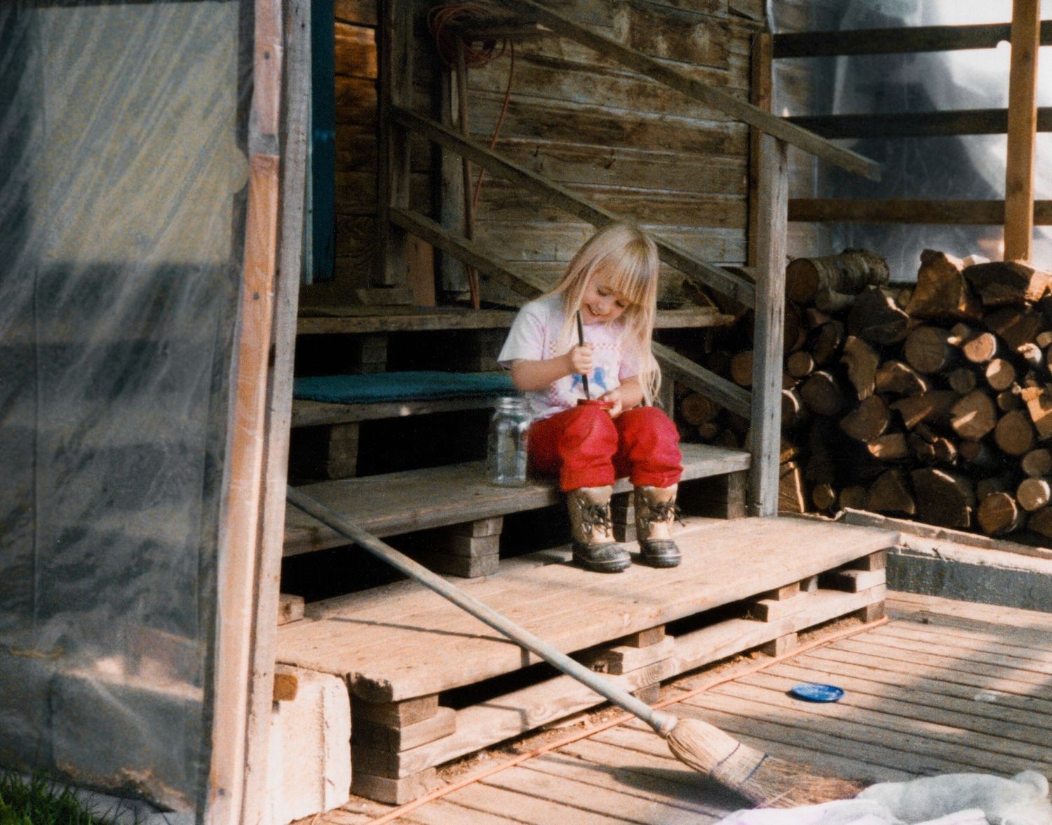 Small girl sitting on porch poking holes in lid of jar to create a terrarium for caterpillars in Oregon.