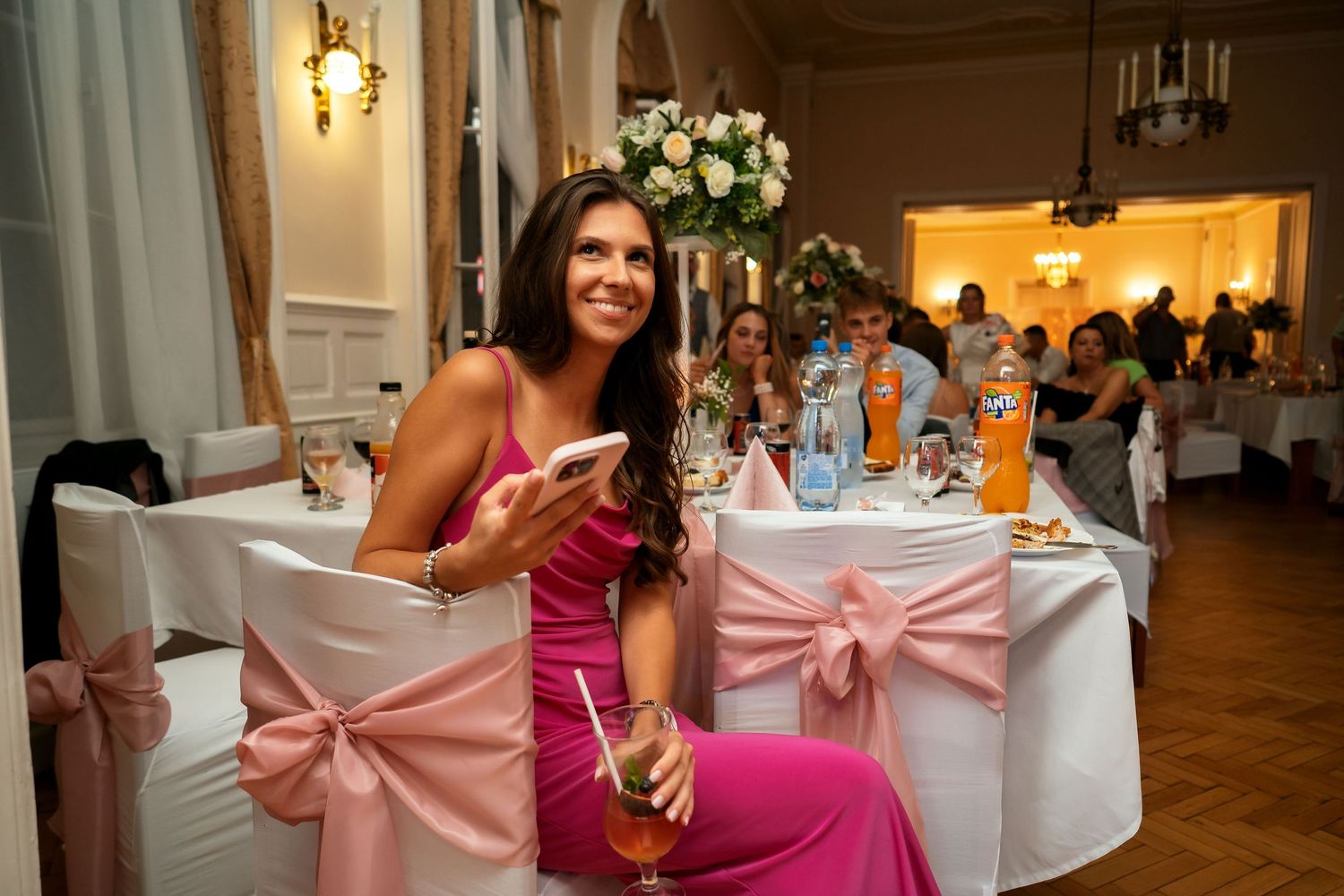 Wedding reception table setting with pink bows and floral centerpiece.