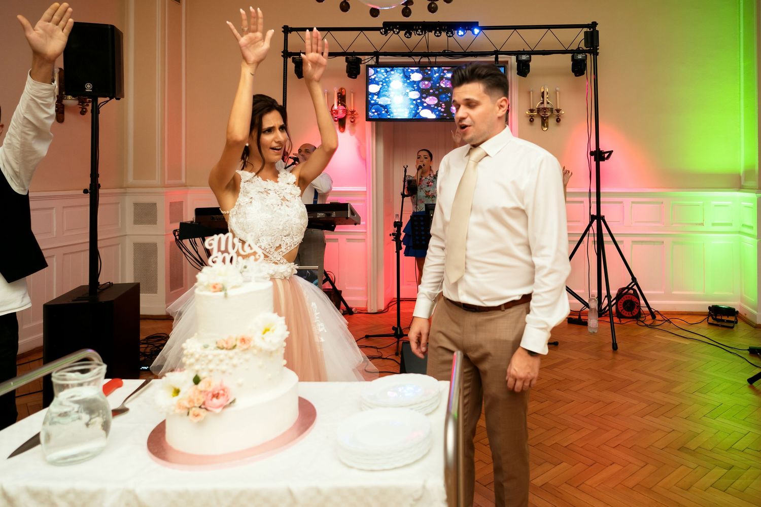 Newlyweds celebrating during cake cutting ceremony at wedding reception.