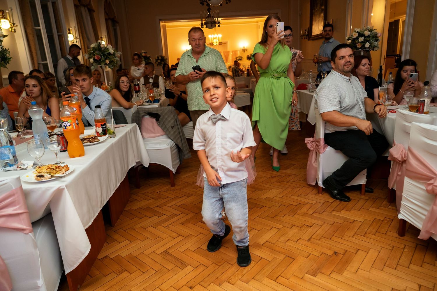 Wedding reception venue with parquet floor and guests seated at decorated tables.