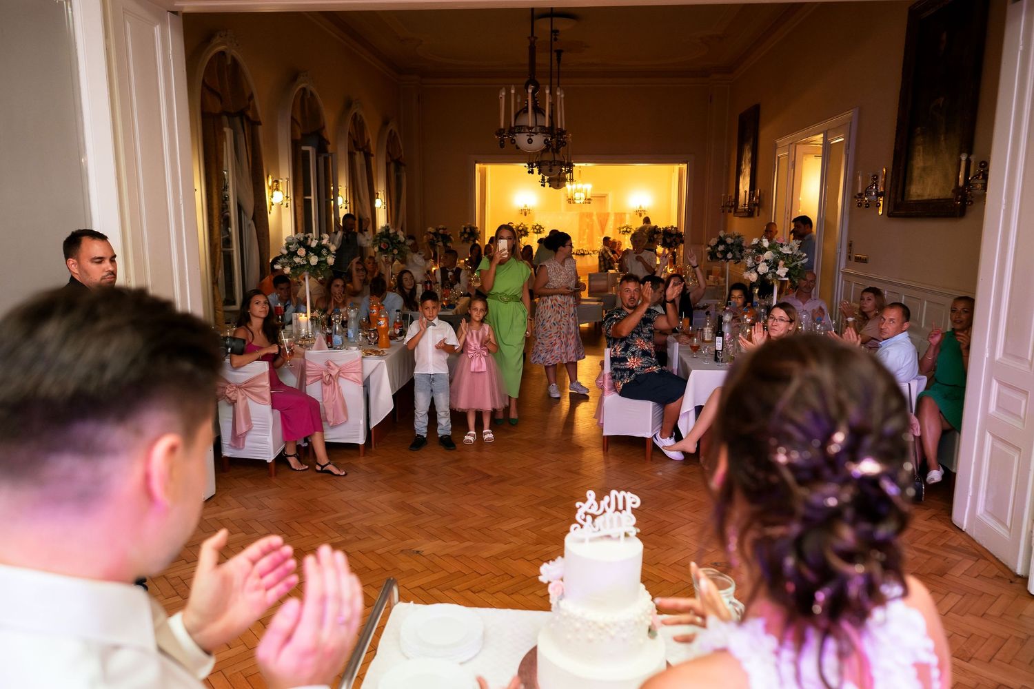 Wedding reception hall filled with guests watching festivities.