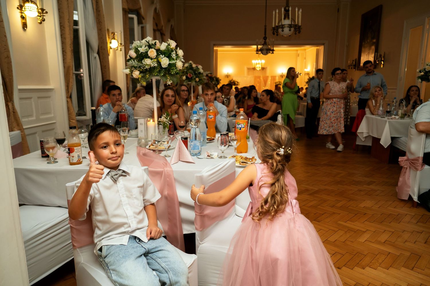Young attendees enjoying refreshments at an elegant wedding reception with pink decor.