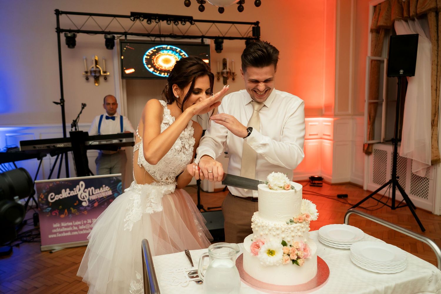Couple sharing a playful moment while cutting their wedding cake at reception.